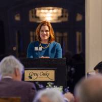 Foundation Director Laura Aikens standing at podium, speaking to audience